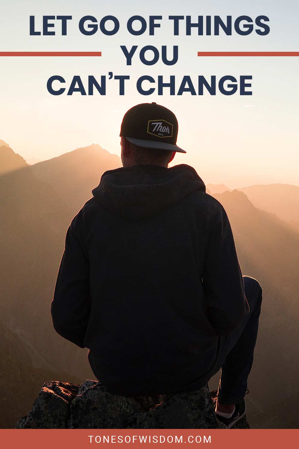 Man wearing a baseball hat sitting on a mountain top - Let Go Of Things You Can't Change